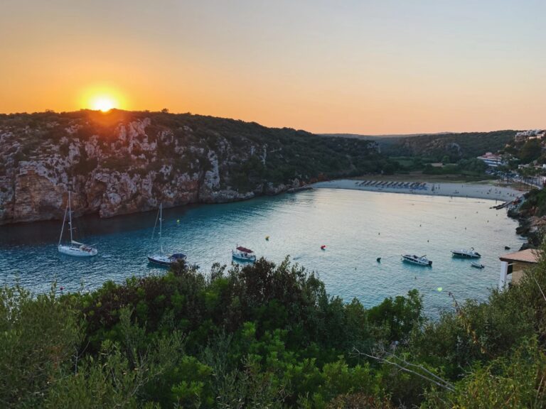 Sunset over tranquil Cala en Porter, one of the best beaches in Menorca