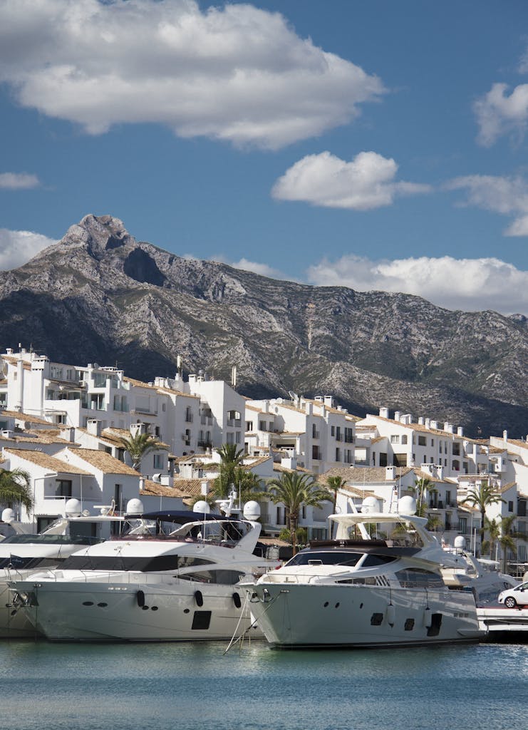 Southern Spain Itinerary 10 Days 17 Elegant yachts docked at a Mediterranean harbor with picturesque mountain and town backdrop.