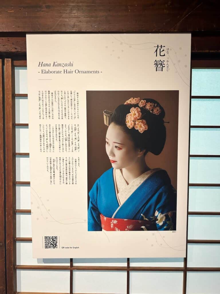 ULTIMATE 10 Day Japan Travel Itinerary 10 A poster features a woman in traditional Japanese attire with elaborate floral hair ornaments. The title reads “Hana Kanzashi - Elaborate Hair Ornaments.” Japanese and English text describes the ornaments, perfect inspiration for your 10 day Japan travel itinerary. A QR code appears below.