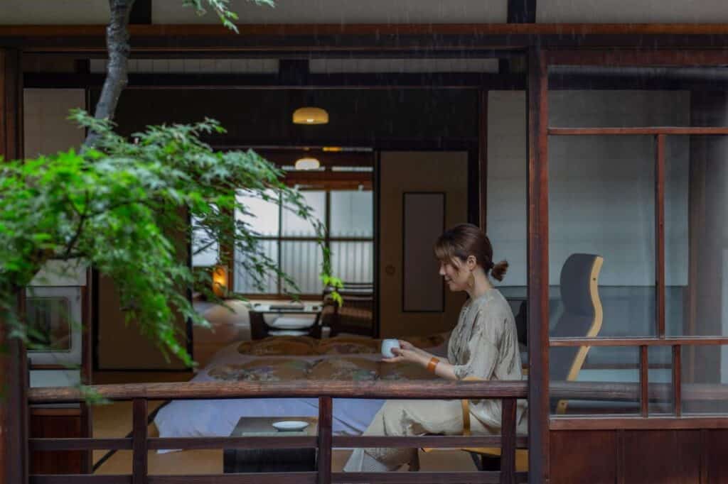 8 UNIQUE Miyajima Ryokans, Hiroshima 21 Woman enjoying tea in serene room.