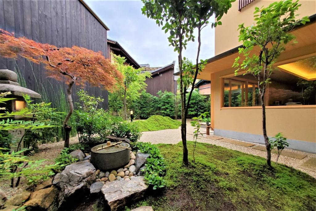 8 UNIQUE Miyajima Ryokans, Hiroshima 39 A serene Japanese garden with moss-covered ground, a stone lantern, a water basin, lush green trees, and a traditional wooden house with large windows on the right—evoking the tranquil atmosphere of Miyajima ryokans.