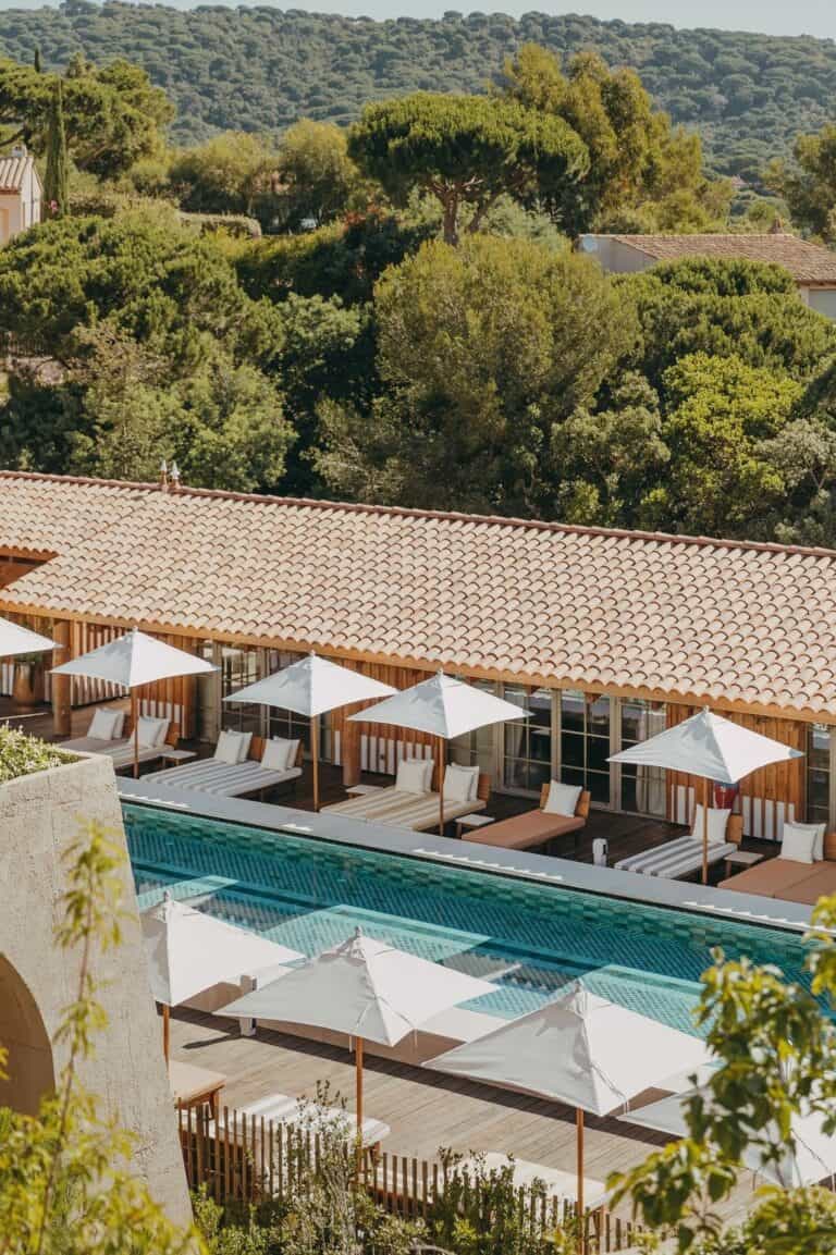 Elegant poolside with sun loungers and umbrellas.