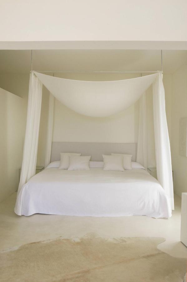 Unique Agroturismos in Mallorca 3 A minimalist bedroom inspired by agroturismos in Mallorca, with a large bed covered in white linens and pillows, a simple white canopy above, and neutral walls and flooring that create a calm, airy atmosphere.
