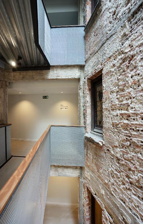 8 Unique Boutique Hotels in Bilbao Spain 8 A modern indoor walkway with metal railings sits beside exposed brick walls and a window, capturing the industrial-rustic charm often found in boutique hotels in Bilbao. The area is well-lit, with smooth floors and crisp white walls.