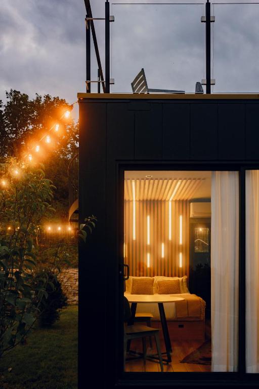 11 Unique Hotels in Georgia You Can't Miss! 36 Evening view of a modern cabin with string lights in the garden and a well-lit interior visible through a glass doorāone of the unique hotels in Georgia offering unforgettable stays.