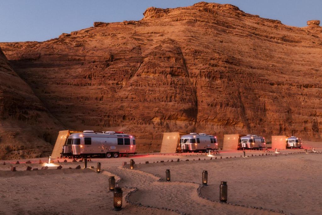 9 Best Hotels in Saudi Arabia: Unique Stays Across the Country 22 Four silver Airstream trailers line the base of a sunlit desert cliff, each with a cozy patio and lantern-lit path—an unforgettable glamping experience among dramatic rock formations at one of the Best Hotels in Saudi Arabia.