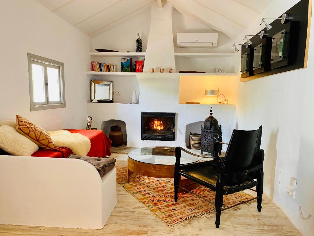 Adults-Only Hotels in Costa del Sol 38 Cozy living room with a white sofa, black armchair, circular glass coffee table, colorful rug, and fireplace—ideal for relaxing after exploring adult only hotels in Costa del Sol. Soft lighting, white walls, and wooden floors create a bright, inviting space.