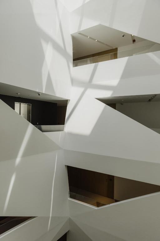 8 TOP Boutique Hotels in Split 25 An interior view of a modern building with multiple open walkways, geometric white walls, and sunlight casting angular shadows—offering design inspiration for those researching Where to Stay in Split with an eye for layered, abstract architecture.