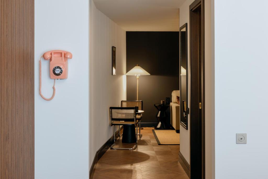 11 Unique Hotels in Georgia You Can't Miss! 20 A hallway with a vintage pink rotary phone on the wall leads to a room with a modern black and beige chair, a floor lamp, and dark accent wallsāechoing the minimal, stylish vibe found in unique hotels in Georgia.