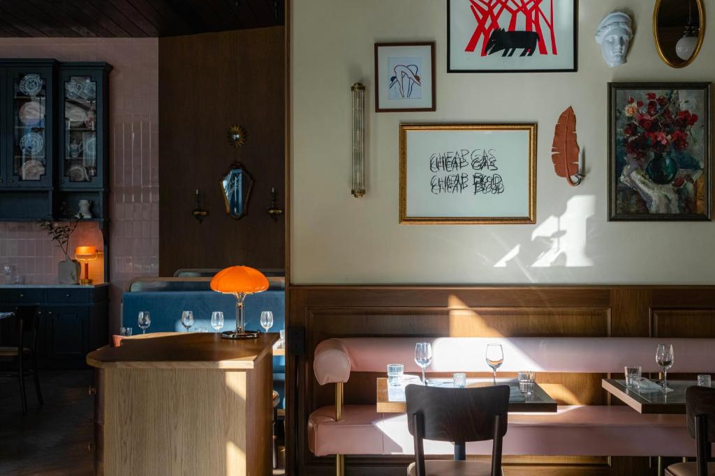 11 Unique Hotels in Georgia You Can't Miss! 19 A cozy restaurant interior with sunlit pink cushioned benches, set tables, wall art, and decorative items. Warm lighting and wooden furniture create a welcoming atmosphere reminiscent of unique hotels in Georgia.