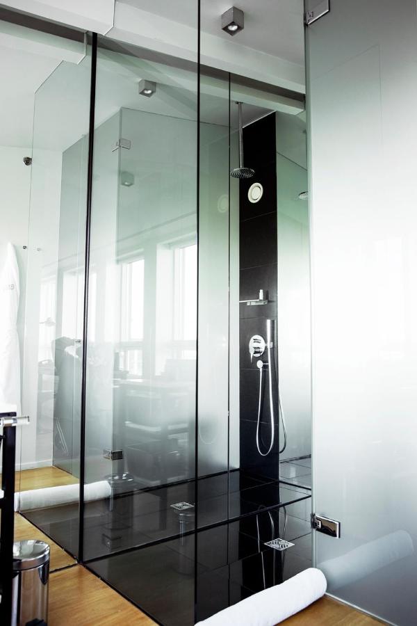 Where to Stay in Reykjavík: Top Guide 9 A modern glass shower with black tile interior and chrome fixtures, like those in top hotels when searching where to stay in Reykjavik; natural light streams through large windows, reflecting off sleek surfaces.