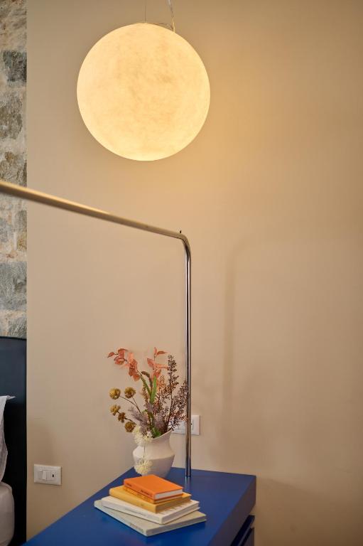 8 TOP Boutique Hotels in Split 19 A round, glowing pendant light hangs above a blue table with a white vase of dried flowers and books, set against a beige wall—showcasing a stylish interior and offering inspiration on where to stay in Split.