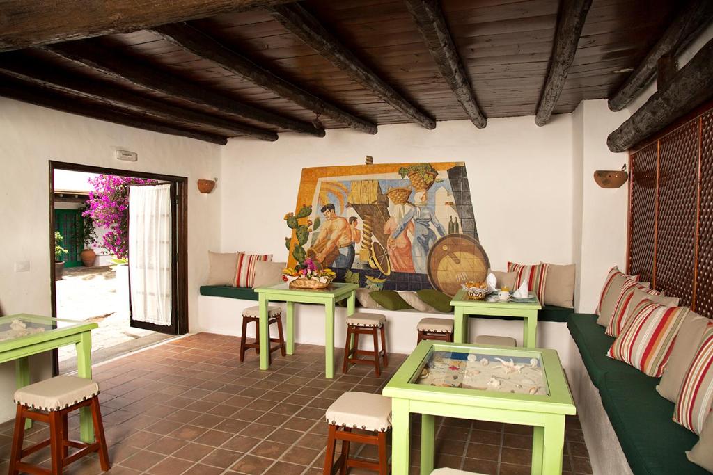 Unique Adults Only Hotels in Lanzarote 27 A cozy room with green tables, cushioned benches, and stools, featuring a colorful mural and wooden beam ceiling. Sunlight streams in from an open door, reminiscent of the inviting charm often found in Adults Only Hotels in Lanzarote.