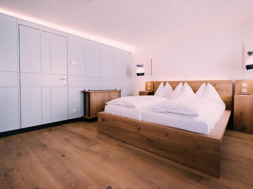 Unique Boutique Hotels in Salzburg 36 Minimalist bedroom with light wood flooring, a large wooden bed with white linens, built-in white cabinets, and soft lighting—evoking the serene style often found in boutique hotels in Salzburg.