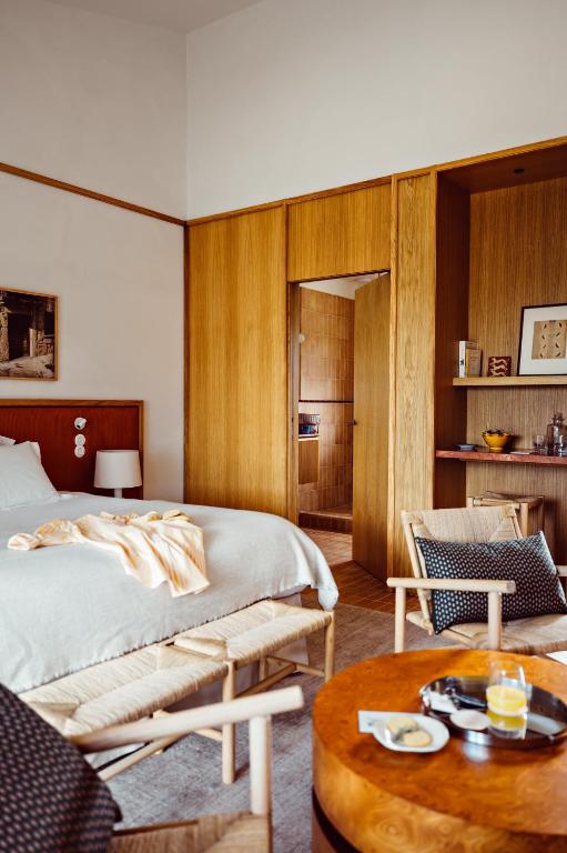 11 Unique Places to Stay in Provence 40 A cozy hotel room with a neatly made bed, wooden furniture, a small table set for breakfast, and built-in shelves. Warm earthy tones create comfort, making it one of the unique places to stay in Provence.