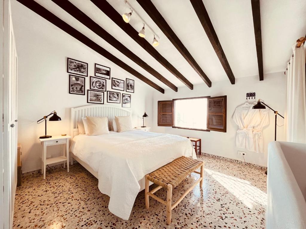 Adults-Only Hotels in Costa del Sol 35 Bright bedroom with exposed wooden ceiling beams, a double bed with white linens, bedside tables with lamps, and framed photos above the bed—an inviting retreat in one of the finest adult only hotels in Costa del Sol.