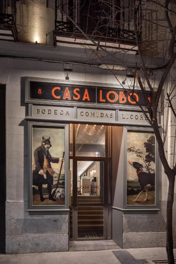 Where to Stay in Madrid: 14 Best Hotels 15 The entrance of Casa Lobo is lit at night, with large paintings of animals in human clothing on either side. This unique spot is a must-see for those searching for where to stay in Madrid first time, marked by its black and red Casa Lobo sign above the door.