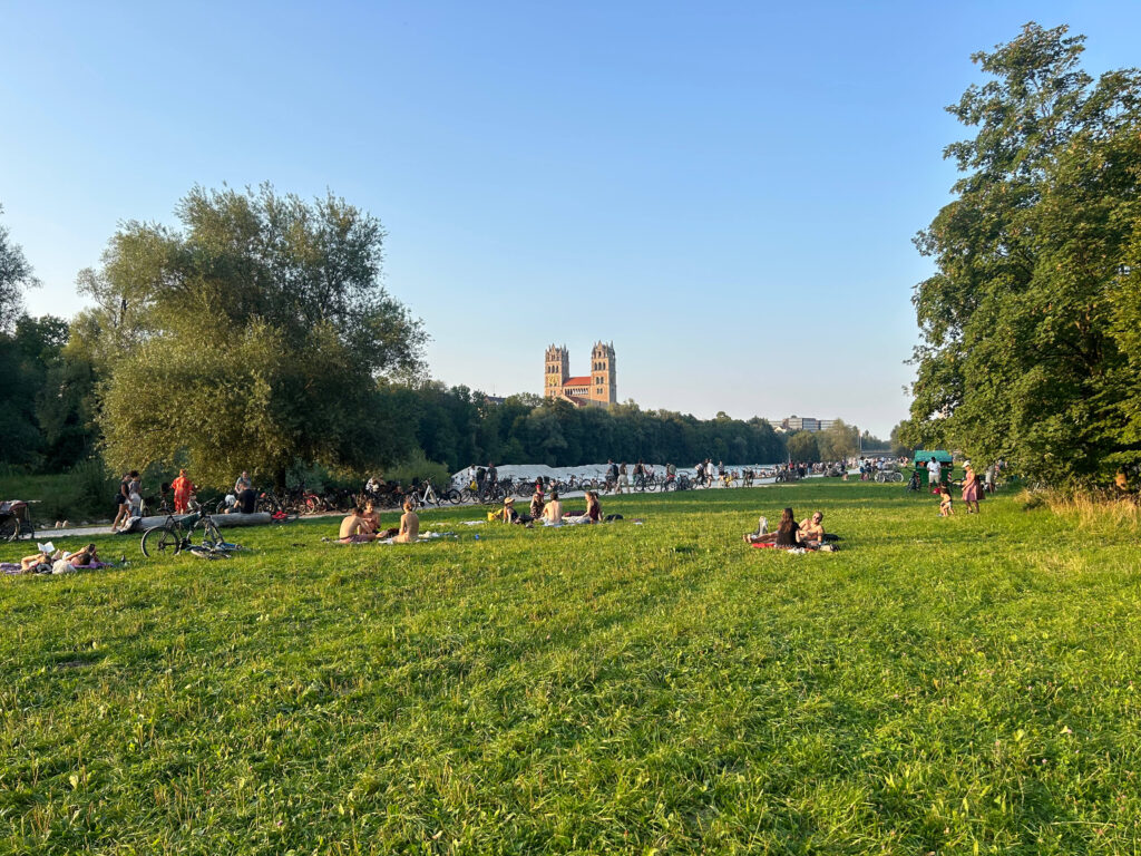 Authentic Boutique Hotels in Munich 1 green field with people on a summer day by the isar river in munich