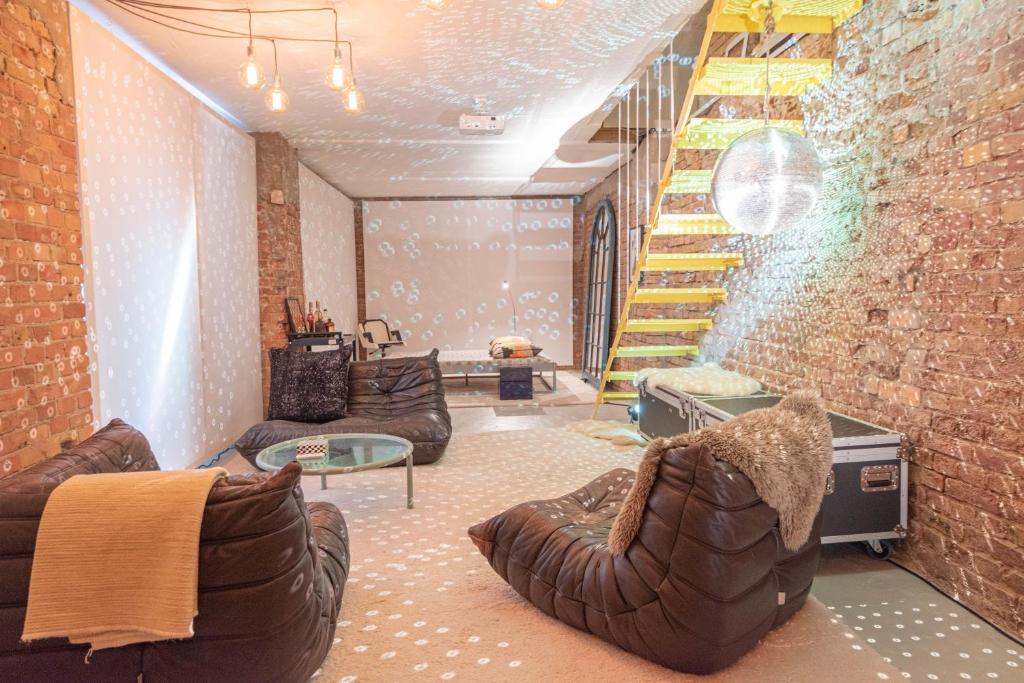 Boutique Hotels in Berlin Kreuzberg 27 A cozy living room with exposed brick walls, brown leather bean bag chairs, a glass coffee table, and a yellow wooden staircaseāreminiscent of the eclectic style found in boutique hotels in Berlin Kreuzberg. A disco ball reflects light around the room.