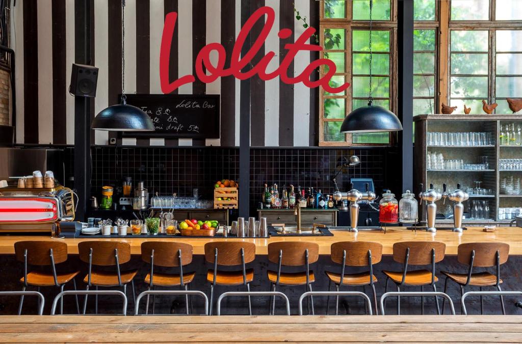 11 Unique Hotels in Georgia You Can't Miss! 11 A modern bar with wooden seating, a variety of drinks, fruit, and bar equipment on the counter. Large windows let in natural light. The word Lolita is written in large red script above the barāperfect for fans of unique hotels in Georgia.