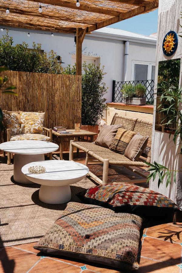 Where to Stay in Madrid: 14 Best Hotels 43 Cozy outdoor patio with rattan furniture, patterned pillows, two round white tables, woven rugs, and bamboo fencing—perfect inspiration if you're searching where to stay in Madrid first time for a warm, inviting atmosphere under a pergola with string lights.