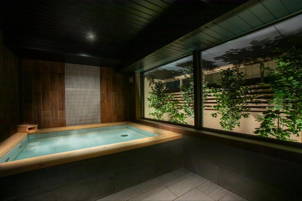 Looking for the Best Ryokan in Takayama? 17 A serene indoor Japanese-style bath at the Best Ryokan in Takayama, featuring wooden trim, soft lighting, and large windows overlooking lush green plants for a tranquil and relaxing atmosphere.