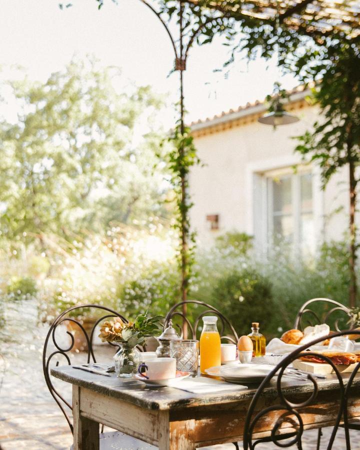 25 Weekend Trips from Madrid Max. 2h Away 3 A rustic outdoor table set for breakfast with orange juice, coffee, pastries, and flowers under a vine-covered pergola—perfect inspiration for weekend trips from Madrid, surrounded by sunlight and lush greenery.