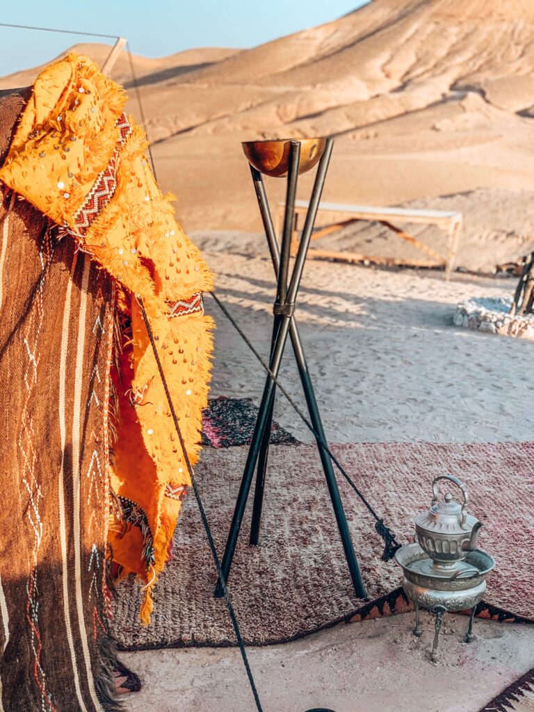 8 SPECTACULAR Agafay Desert Camps 46 A tent with a blanket and a teapot on a rug in the Agafay Desert camps.