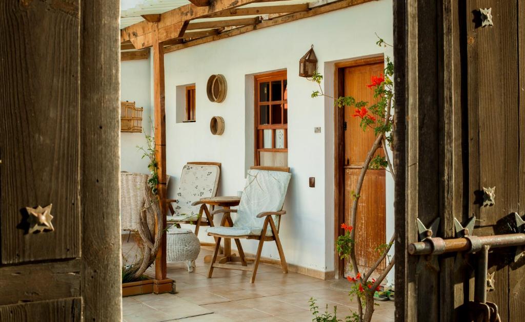 Adults Only Hotels in Fuerteventura 15 A cozy porch with two wooden chairs and a small table, surrounded by potted plants and hanging hats, seen through an open wooden gate—capturing the rustic, inviting charm of adults only hotels in Fuerteventura.