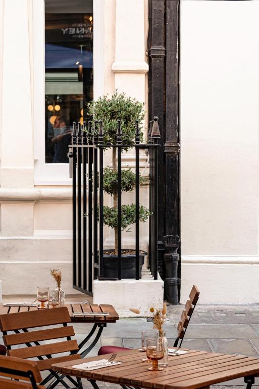15 Best Boutique Hotels in London, UK 53 Outdoor café with wooden tables and chairs, each table set with glasses and dried flower arrangements. In the background, a potted topiary stands behind a black wrought-iron fence—reminiscent of boutique hotels in London.