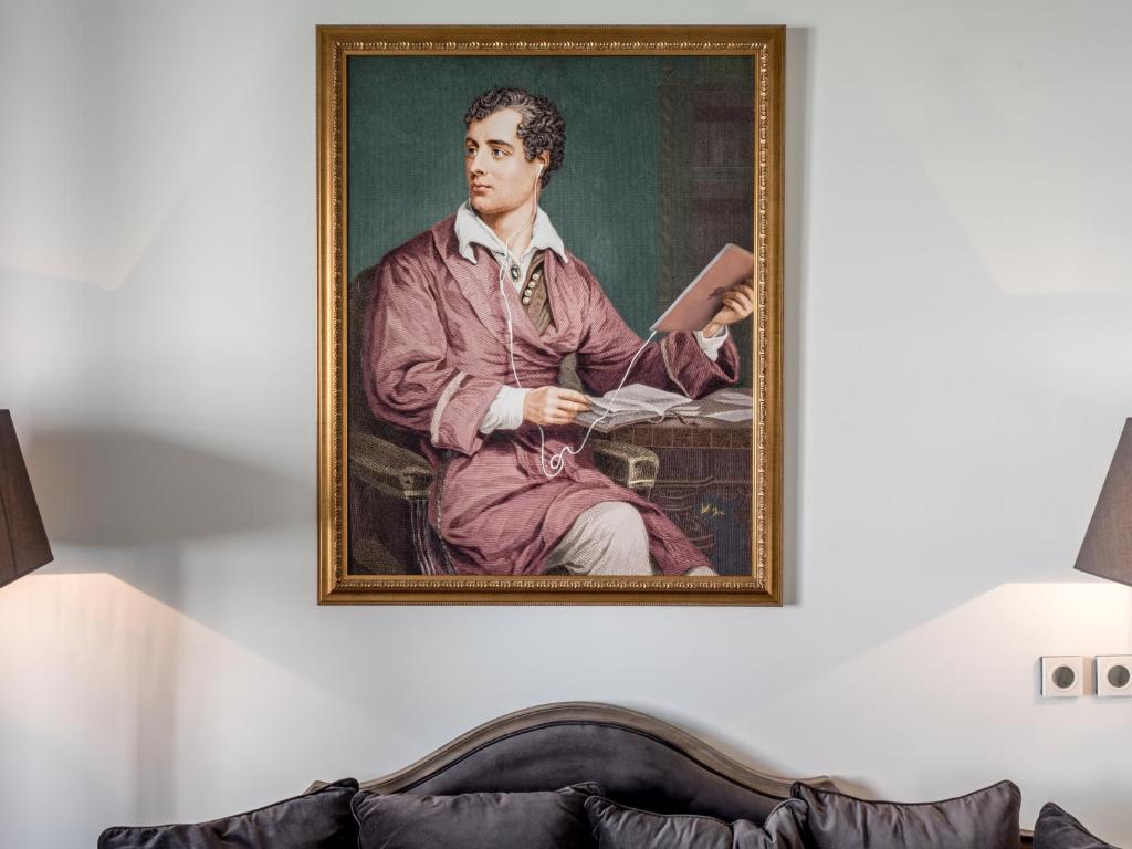 Most Unique Boutique Hotels in Dubrovnik 12 A framed portrait of a man in a maroon robe holding papers hangs above a gray couch, flanked by two black lamps—an elegant setting often found in boutique hotels in Dubrovnik.