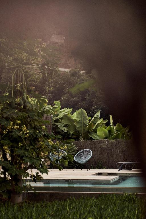 11 UNIQUE Boutique Hotels in Tenerife 37 Two modern outdoor chairs sit on a sunny patio beside a swimming pool, surrounded by lush tropical foliage, evoking the tranquil and inviting ambiance found at boutique hotels in Tenerife.
