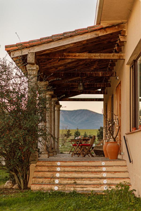 25 Weekend Trips from Madrid Max. 2h Away 31 A rustic porch with stone steps and columns, a wooden roof, and a small table with chairs overlooks a scenic landscape—perfect inspiration for weekend trips from Madrid, with a mountain view glowing at sunset.