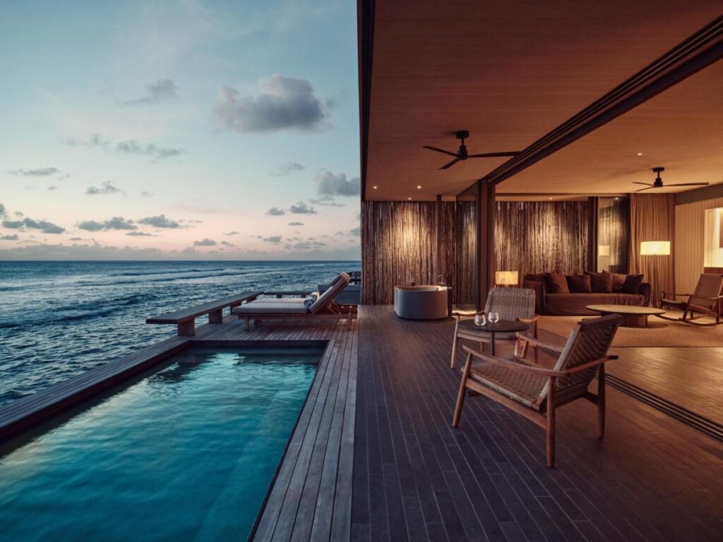 Best Luxury Hotels in Maldives for Your Dream Vacation 3 A luxurious open-air villa at sunset, featuring a private pool, lounge chairs, and a spacious living area with modern decor—perfect for those seeking the experience of the best luxury hotels in Maldives.