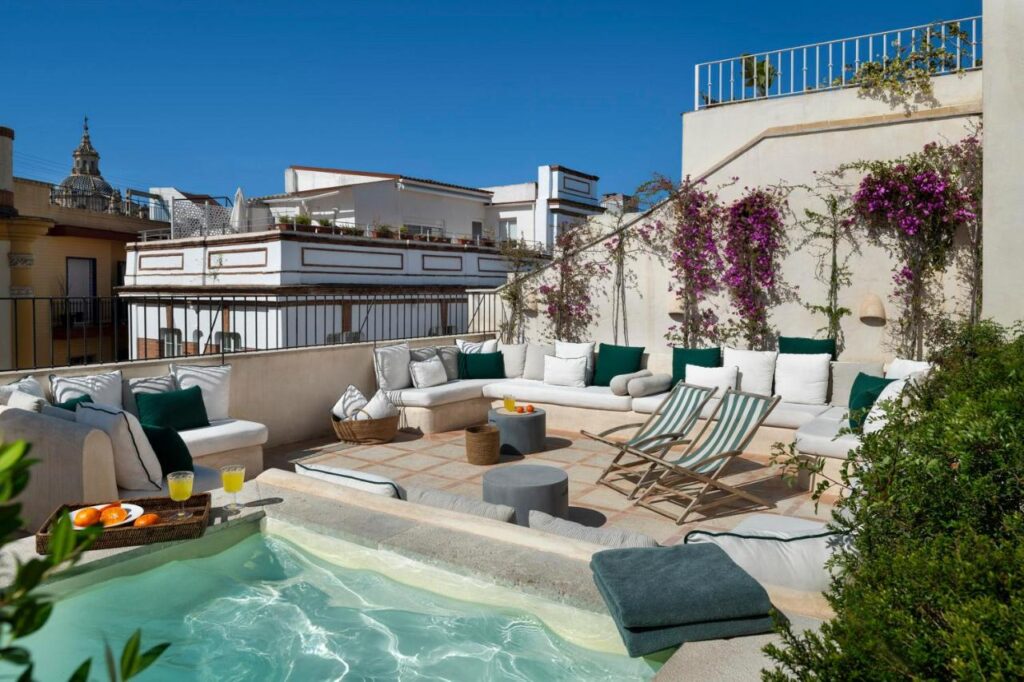 1 day in Seville Spain: My Favorite City 8 Perfect for spending 1 day in Seville, Spain, this rooftop terrace features cushioned white sofas, striped deck chairs, a small pool, flowering vines, and refreshments set under a clear blue sky.