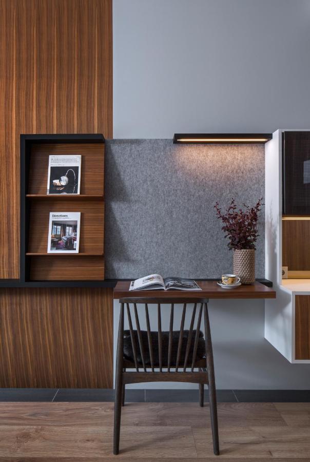 Where to Stay in Reykjavík: Top Guide 17 A modern home office features a wooden desk with an open book, a cup and saucer, a vase with dark red foliage, and magazines—ideal for researching where to stay in Reykjavik under the warm glow of an overhead light.