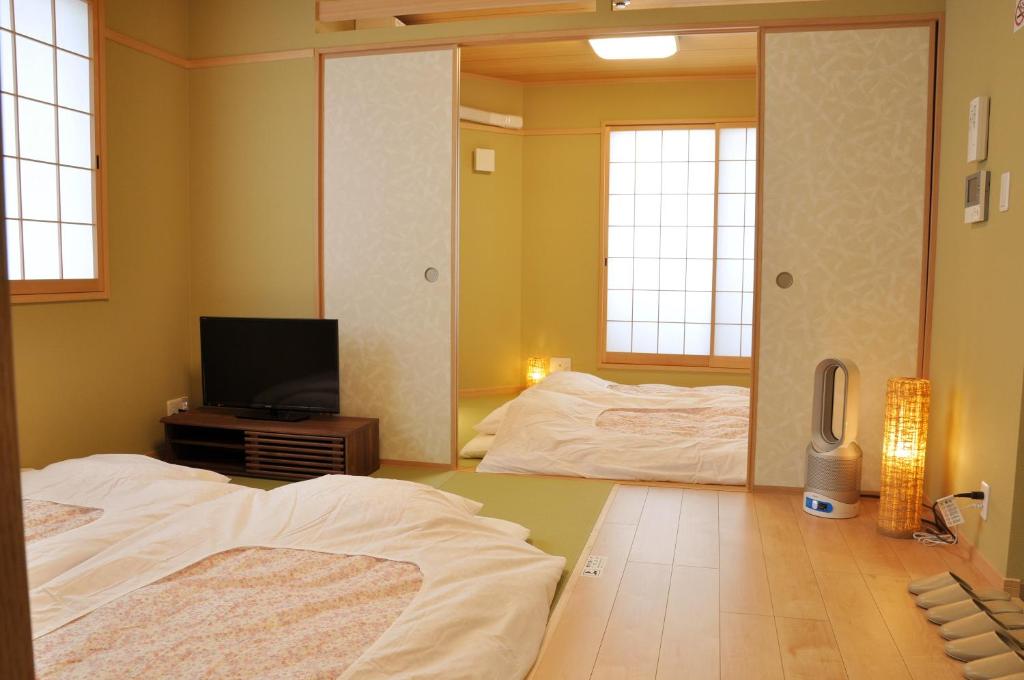 8 BEST Ryokans in Osaka 9 A traditional Japanese room inspired by ryokans in Osaka, featuring tatami mats, futon beds on the floor, sliding shoji doors, soft lighting, a small TV, and a modern air purifier. The minimalist decor includes light wooden accents.
