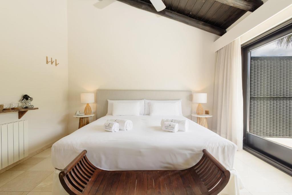 Adults-Only Hotels in Costa del Sol 25 Bright, modern bedroom at one of the best adult only hotels in Costa del Sol, featuring a large neatly made bed, bedside tables with lamps, a wooden bench at the foot of the bed, and a large window flooding the space with natural light.