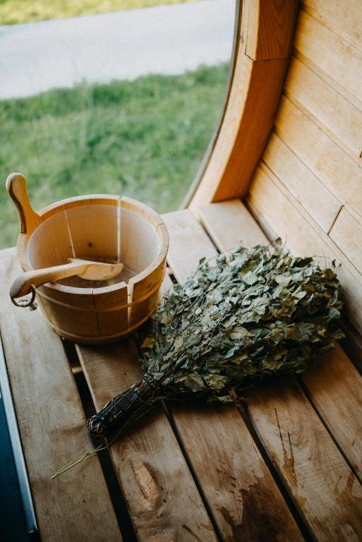 11 Unique Hotels in Georgia You Can't Miss! 35 A wooden sauna bucket with a ladle and dried birch branches rest on a bench inside a sauna at one of the unique hotels in Georgia, sunlight streaming through a curved window.