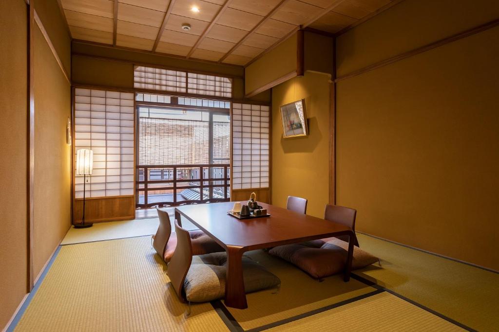 7 UNIQUE Ryokans in Gion Kyoto 29 A traditional Japanese room with tatami mats, a low wooden table surrounded by floor cushions, shoji paper sliding doors, and a floor lamp—reflecting the serene elegance of ryokans in Gion Kyoto—with natural light streaming in.