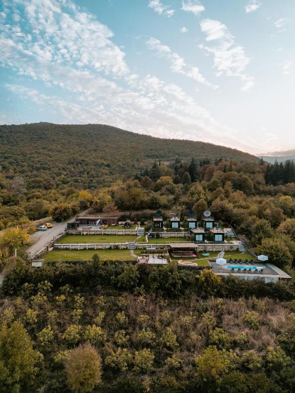 11 Unique Hotels in Georgia You Can't Miss! 34 Aerial view of one of the unique hotels in Georgia, featuring several buildings and green lawns nestled among dense trees and hills under a partly cloudy sky at sunset.