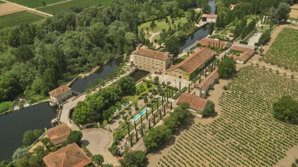 25 Weekend Trips from Madrid Max. 2h Away 22 Aerial view of a large estate with red-roofed buildings, gardens, and a pool, surrounded by vineyards and trees beside a winding river—an ideal spot for weekend trips from Madrid in a peaceful rural landscape.