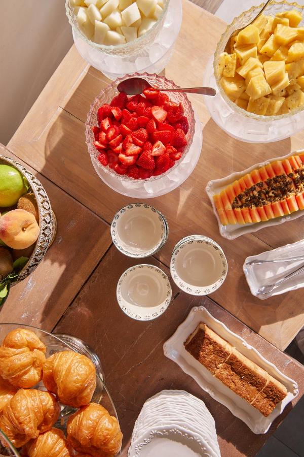 25 Weekend Trips from Madrid Max. 2h Away 88 A breakfast spread perfect for weekend trips from Madrid, featuring bowls of strawberries, pineapple, and melon, a plate of papaya, fresh croissants, a cake slice, and assorted fruit on a wooden table with stacked plates and bowls.