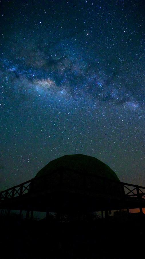 Glamping in the Serengeti: Unique Safari Lodges in Tanzania 2 A silhouette of a domed observatory beneath a clear night sky filled with bright stars and the glowing band of the Milky Way, evoking the magic of glamping in the Serengeti.