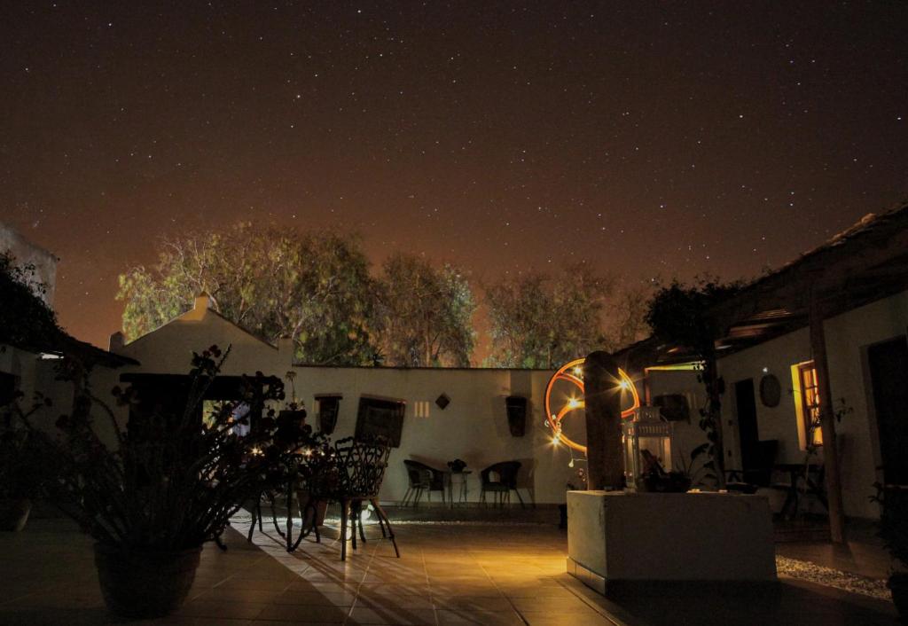 Adults Only Hotels in Fuerteventura 17 A peaceful outdoor patio at night, illuminated by warm lights, with tables and chairs. Surrounded by trees and a white building under a star-filled sky, it evokes the inviting charm of adults only hotels in Fuerteventura.