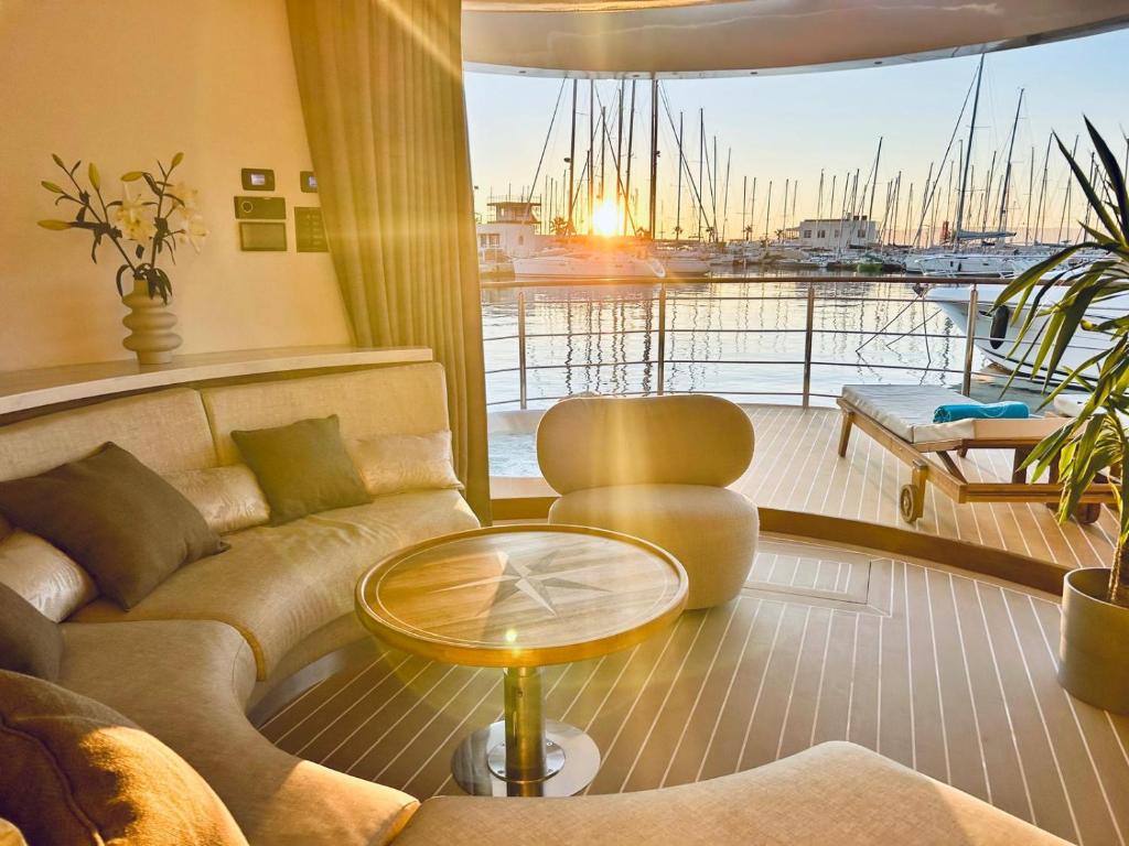 Where to Stay in Split: Hotel & Areas Guide 33 A cozy yacht lounge with a round sofa and table overlooks a marina filled with docked sailboats at sunset—an idyllic spot for those seeking Where to Stay in Split, as sunlight streams in, creating a warm, relaxing atmosphere.