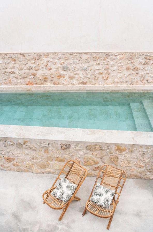 25 Weekend Trips from Madrid Max. 2h Away 72 Two rattan lounge chairs with patterned cushions sit beside a small, rectangular outdoor pool—an inviting scene reminiscent of stylish retreats found on weekend trips from Madrid, surrounded by light stone walls and a minimalist, neutral-toned patio.