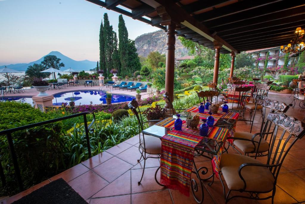 8 UNIQUE Places Where to Stay in Lake Atitlán 33 Outdoor restaurant patio with colorful tablecloths overlooks a vibrant garden, pool area, and distant mountains—an ideal choice for those seeking where to stay in Lake Atitlan amid peaceful and scenic surroundings.