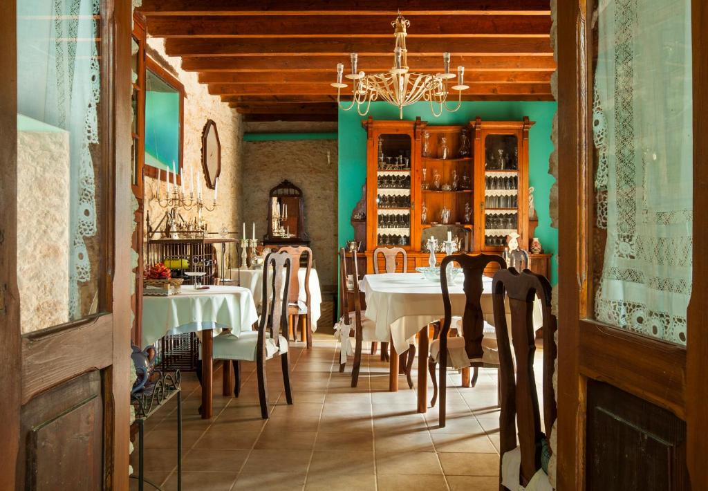 Adults Only Hotels in Fuerteventura 14 A cozy, rustic dining room—like those found in adults only hotels in Fuerteventura—features wooden chairs, round tables with white tablecloths, antique cabinets, a turquoise accent wall, lace curtains, and a chandelier on a wooden beam ceiling.