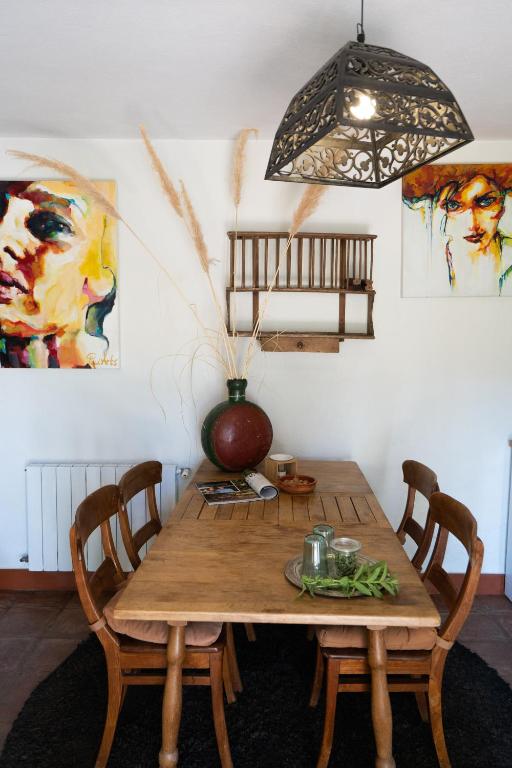 Adults-Only Hotels in Costa del Sol 31 A cozy dining area with a wooden table and chairs, decorated with a vase of dried grasses—like those often found in adult only hotels in Costa del Sol—green beans, candles, and magazines. Colorful portrait paintings brighten the white walls.